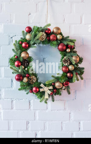 Christmas wreath hanging on white brick wall Stock Photo