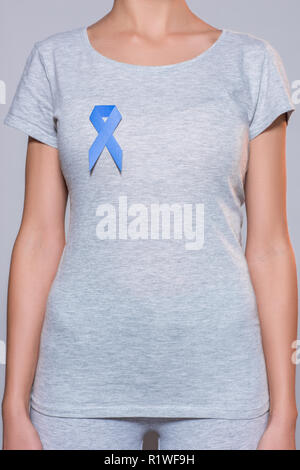 cropped shot of woman in grey tshirt with prostate cancer awareness blue ribbon on grey backdrop Stock Photo