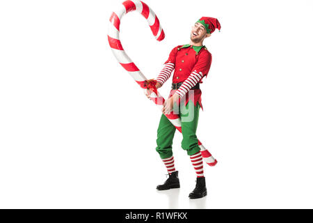 cheerful man in christmas elf costume riding big candy cane isolated on white Stock Photo