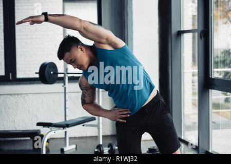 young sportsman doing stretching exercise at gym Stock Photo