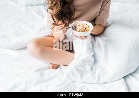 cropped view of girl having oatmeal for breakfast in bed Stock Photo