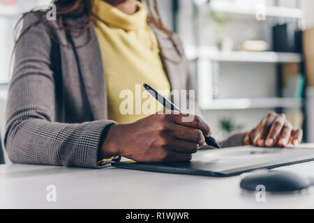 midsection of african american designer using graphic tablet at desk in modern office Stock Photo