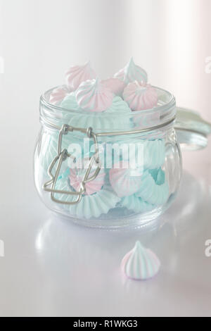 Light Pink and blue meringues in glass jar on pink background, vertical composition Stock Photo