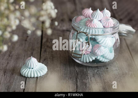 Light Pink and blue meringues in glass jar on dark background Stock Photo