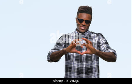Young african american man wearing sunglasses over isolated background smiling in love showing heart symbol and shape with hands. Romantic concept. Stock Photo