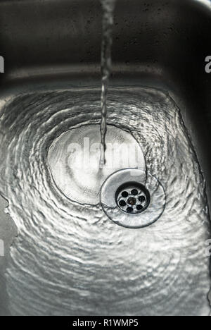 Chrome kitchen sink with pouring water. Stock Photo