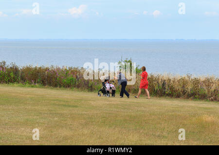 Two women walking along the cliff top path at Hunstanton, with the elderly woman is pushing the pram. The Wash is in the background. Norfolk, UK Stock Photo