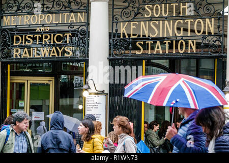 London England,UK,South Kensington Station,tube subway outside above ground,entrance,sign,umbrella,Union Jack,raining rain weather,man men male,woman Stock Photo