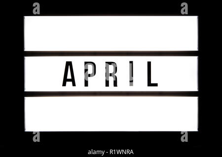 APRIL text in a light box, isolated over a black background. Stock Photo