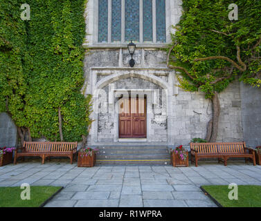 Two benches and flower pots in front of an entrance with a wooden door Stock Photo