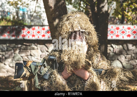 Camouflaged sniper keeps rifle . Soldier dressed in ghillie camouflage on nature. Stock Photo