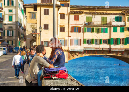 Florence, Italy-June 16, 2017: Romantic interracial couple kissing near landmark bridge Ponte Vecchio Stock Photo