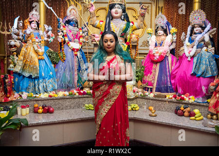 Portrait of an attractive young Hindu woman in front of statues of deities in a temple in Queens, New York City. Stock Photo