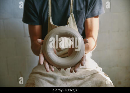 selective focus of professional potter in apron holding clay at pottery studio Stock Photo