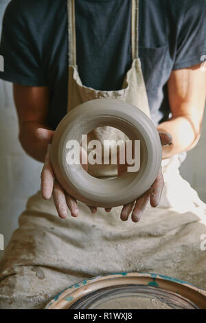 cropped image of professional potter in apron holding clay at pottery studio Stock Photo