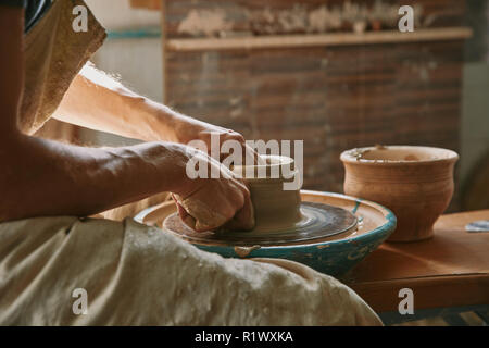 partial view of professional potter working on pottery wheel at workshop Stock Photo