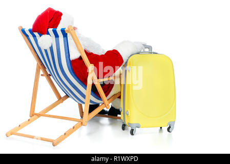 back view of santa claus resting in beach chair with travel bag on white Stock Photo