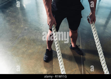 cropped view of sportsman working out with battle ropes Stock Photo
