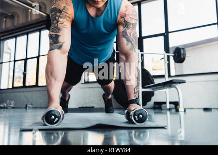 young sportsman exercising with dumbbells in gym on sport mat Stock Photo