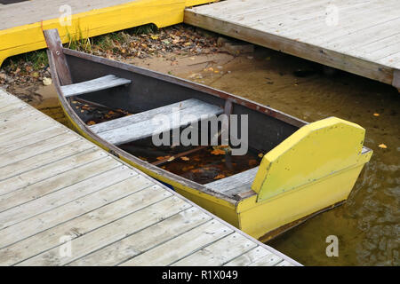 One wooden broken  handmade  aged used boat  on cold fresh lake water near the pier. European autumn  Outdoor shot Stock Photo