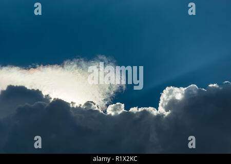 The sun is hidden behind the clouds in the blue sky Stock Photo