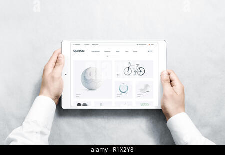 Hands holding tablet with sport webstore mock up on screen, isolated. Training web page interface mockup. Internet website template. Web store screen layout for computer display. Stock Photo