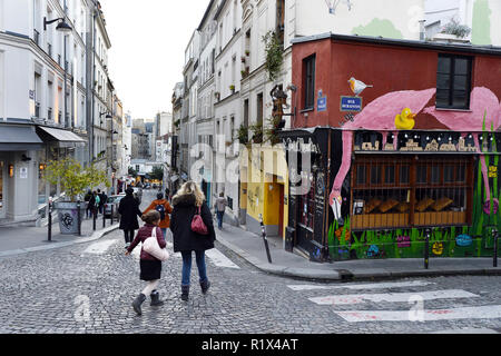 a charming, cobbled street in the Montmartre district of Paris, specifically featuring the corner building of an historic café-restaurant - Paris Stock Photo