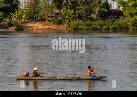 Don Det, Laos - April 22, 2018: Local people rowing a wooden long boat over the Mekong river in southern Laos Stock Photo