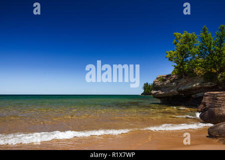 Clear Blue Sky at Sandy Beach with Rocky Coastline. Horizon over water background with copy space. Stock Photo