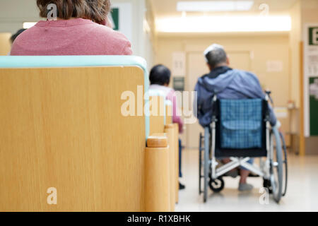 KAGAWA, JAPAN - OCTOBER 24, 2018; Back view of senior man sitting on wheelchair and supporting wife in Mitoyo hospital hallway Stock Photo