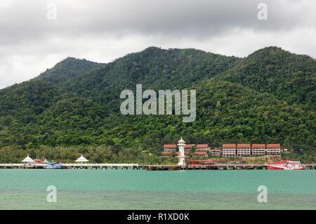 Tropical landscape with turquoise tropical sea, white lighthouse, fishing boat, Bang Bao pier and tropical Koh Chang Island on horizon in Thailand Stock Photo