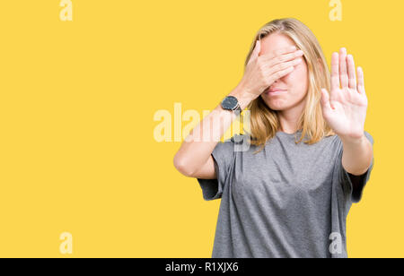 Beautiful young woman wearing oversize casual t-shirt over isolated background covering eyes with hands and doing stop gesture with sad and fear expre Stock Photo