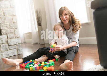 A Mother and child daughter building from toy blocks at home Stock Photo