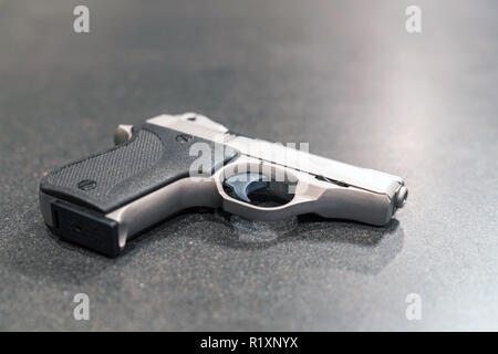 Small Silver Handgun Isolated on Dark Table Stock Photo