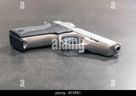 Silver Semi-Automatic Handgun Isolated on Dark Table Stock Photo