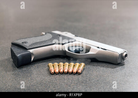 Row of Bullets and Handgun on Black Table Stock Photo