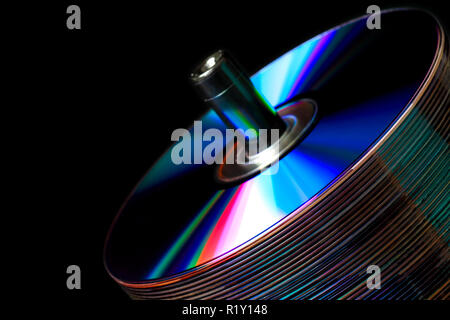 Stack of CDs on a dark background with colored refractive bands Stock Photo