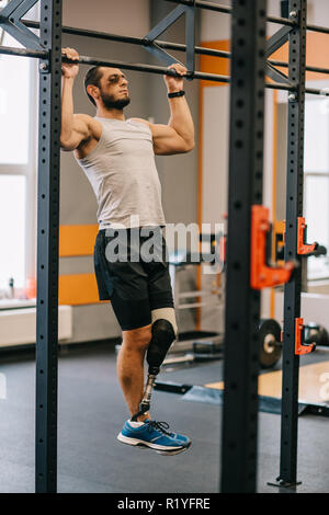 handsome young sportsman with artificial leg doing bul ups at gym Stock Photo