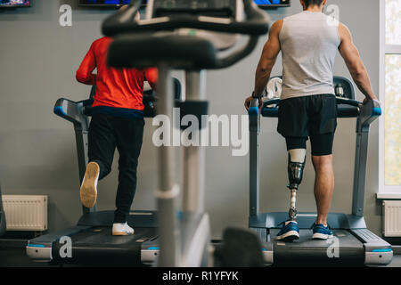 rear view of sportsmen running on treadmills at gym Stock Photo