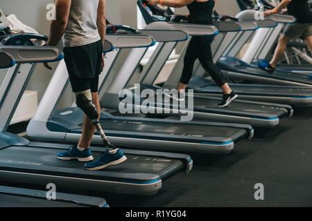 cropped shot of man with artificial leg running on treadmills at gym with other people Stock Photo