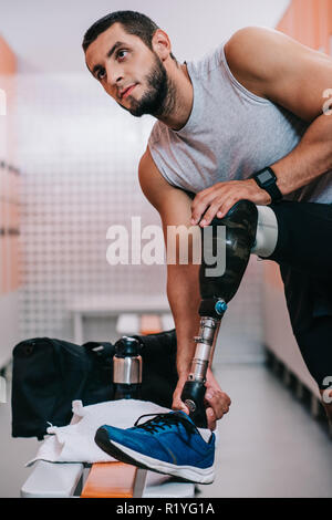 fit young sportsman with artificial leg preparing for training at gym changing room Stock Photo