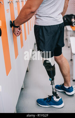 cropped shot of sportsman with artificial leg opening locker with electric key on his wrist at gym changing room Stock Photo