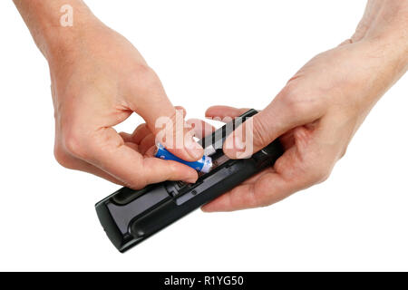 An elderly man replacement a new  fresh battery of LR6 AA  size  in the remote control of a modern TV. Stock Photo