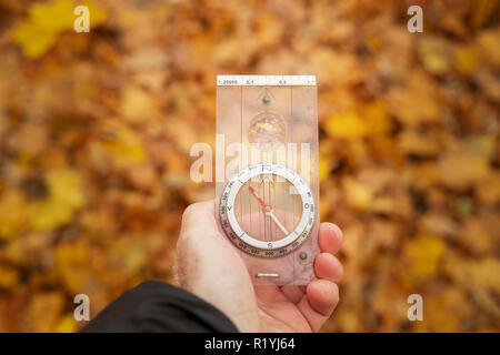 adult man holding compass to find the way in a forest in autumn Stock Photo