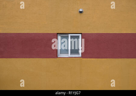 Single small square window  with white frame and minimal red stripe on yellow wall abstract Stock Photo