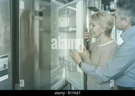 Mature couple chooses refrigerator for their house in shop of household appliances refrigerator Stock Photo