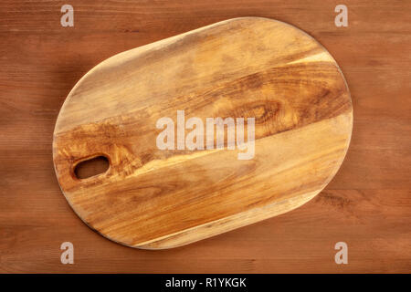 A photo of an old cutting board, shot from the top on a dark rustic texture with a place for text. A cooking background with copy space Stock Photo