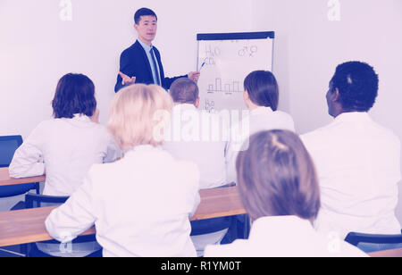 Smiling young male professor giving presentation for medics in convention hall Stock Photo