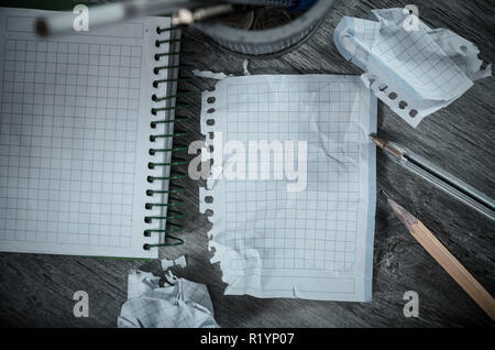 Crumpled empty pages and notebook lying on wooden surface Stock Photo