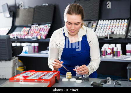 Professional female mechanic selecting fibers color for automobile upholstery in auto workshop Stock Photo